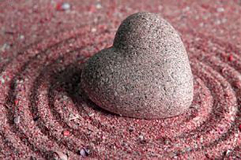 pink stone heart on sand