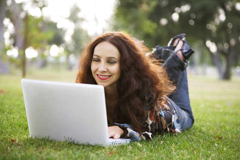 woman using laptop on grass